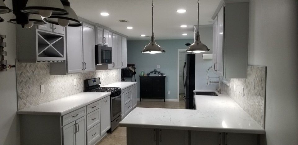 A kitchen with white cabinets , stainless steel appliances , and a large island.