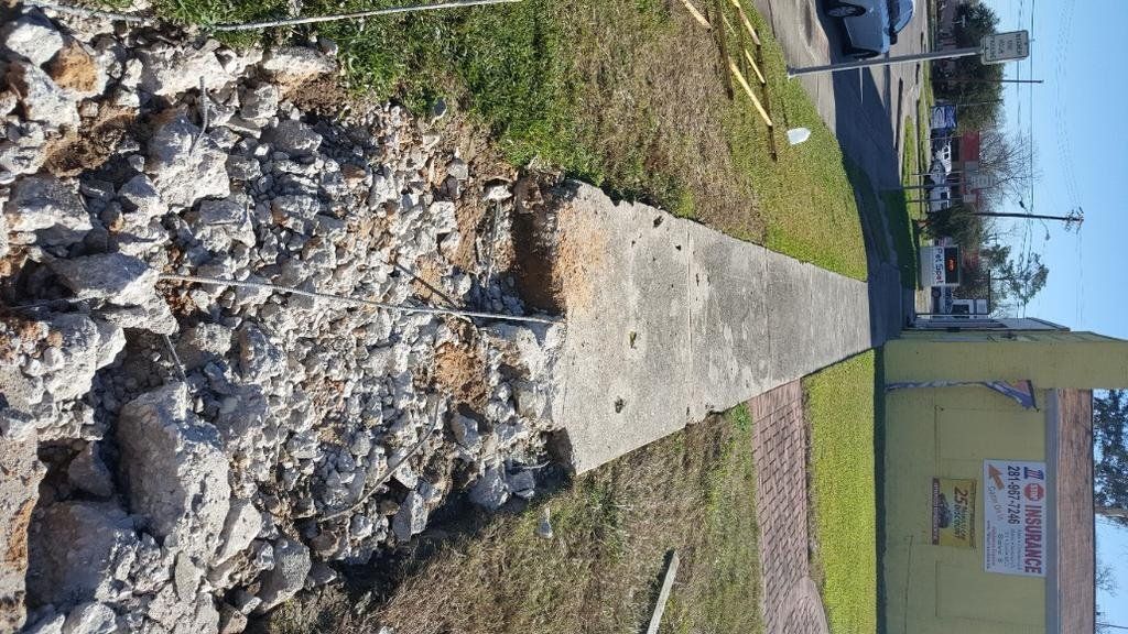 A concrete sidewalk is being demolished in front of a yellow building.