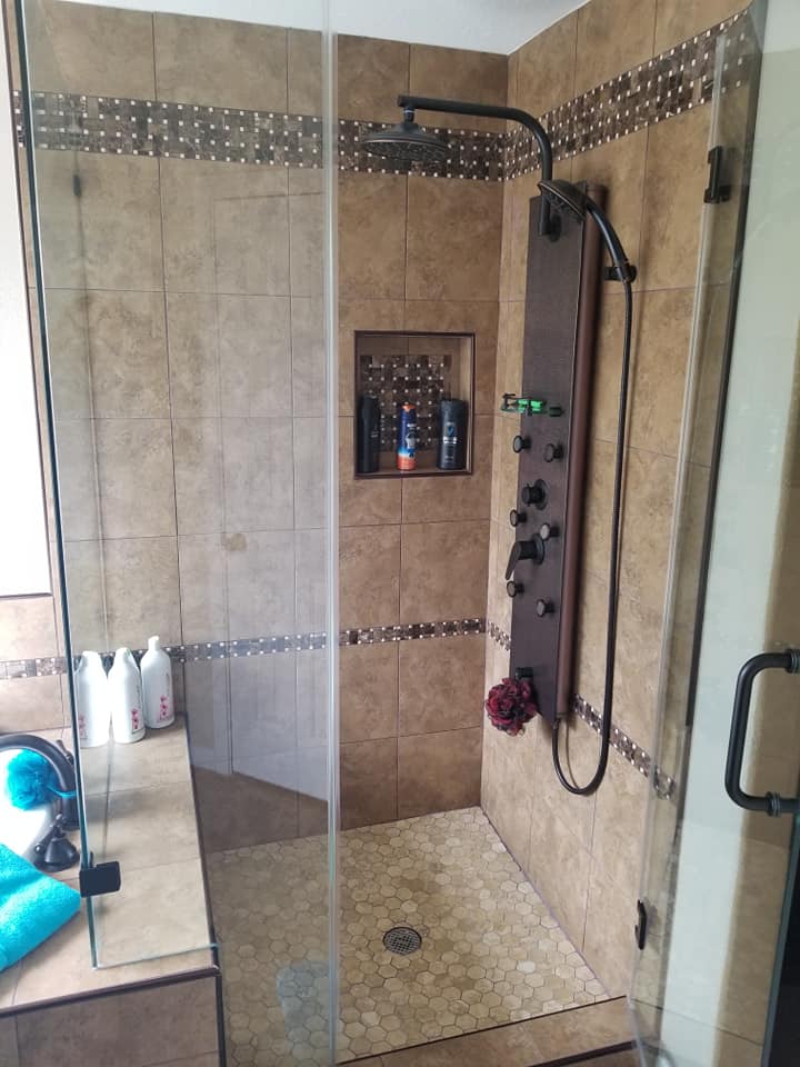 A bathroom with a walk in shower with a glass door.