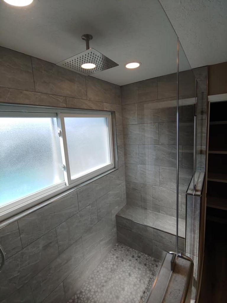 A bathroom with a walk in shower and a window.