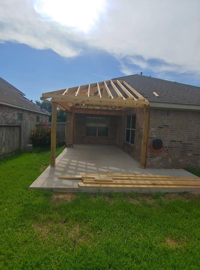 A wooden pergola is being built in the backyard of a house.