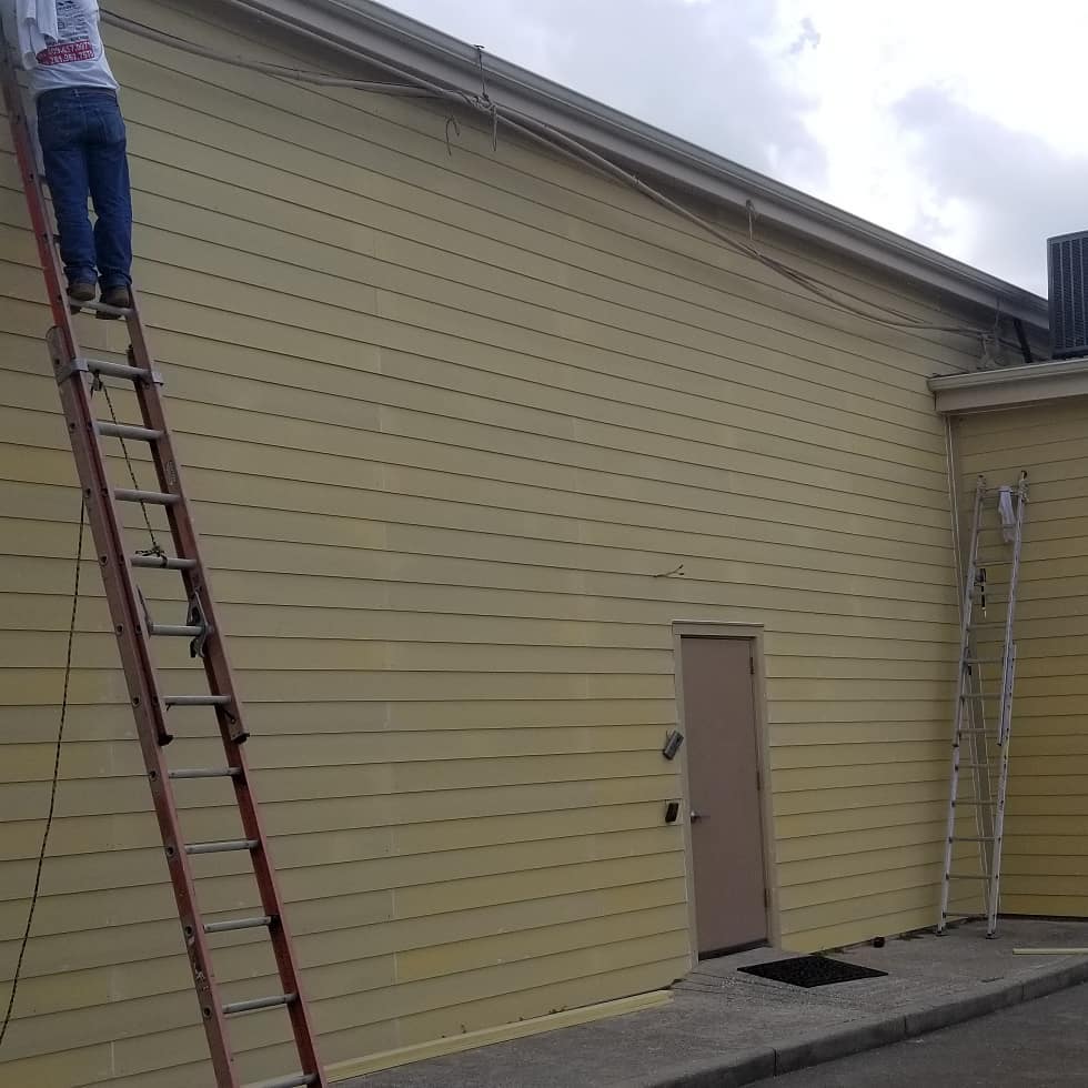 A man is standing on a ladder on the side of a building