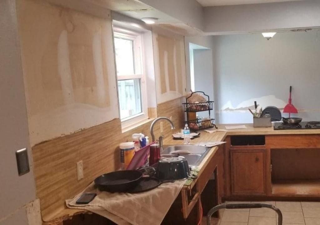A kitchen with a sink , stove , and window is being remodeled.