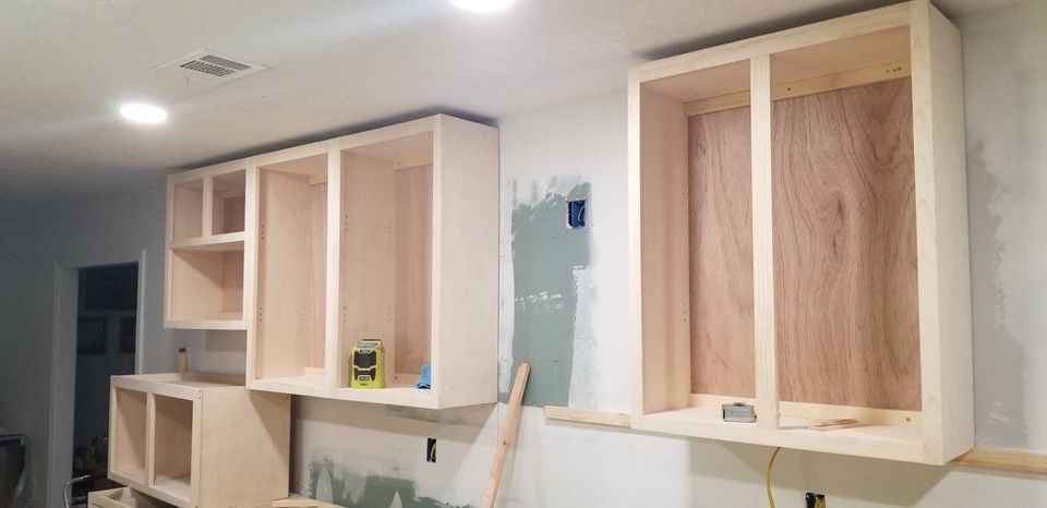 A kitchen with wooden cabinets being built on the wall.