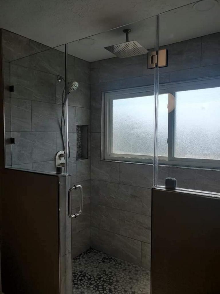 A bathroom with a walk in shower and a window.