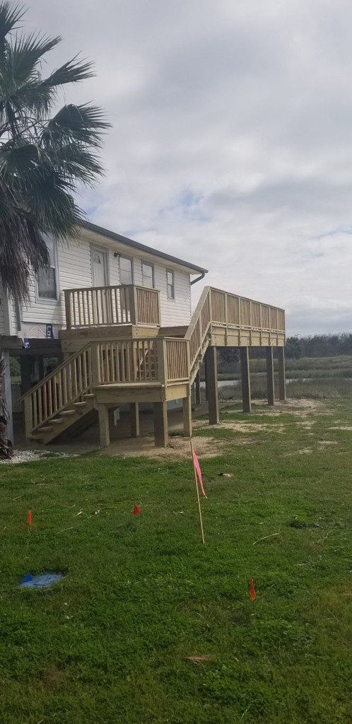 A house with a wooden deck and stairs in front of it.