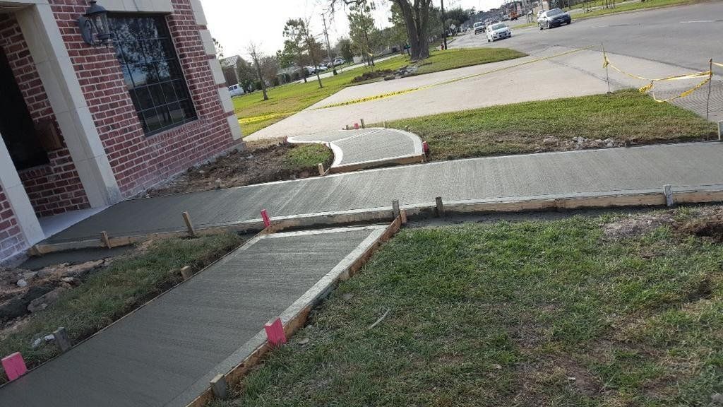 A sidewalk is being built in front of a brick house.