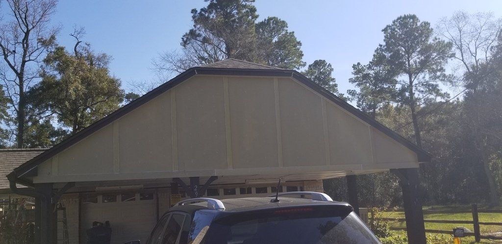 A car is parked under a carport in front of a house.