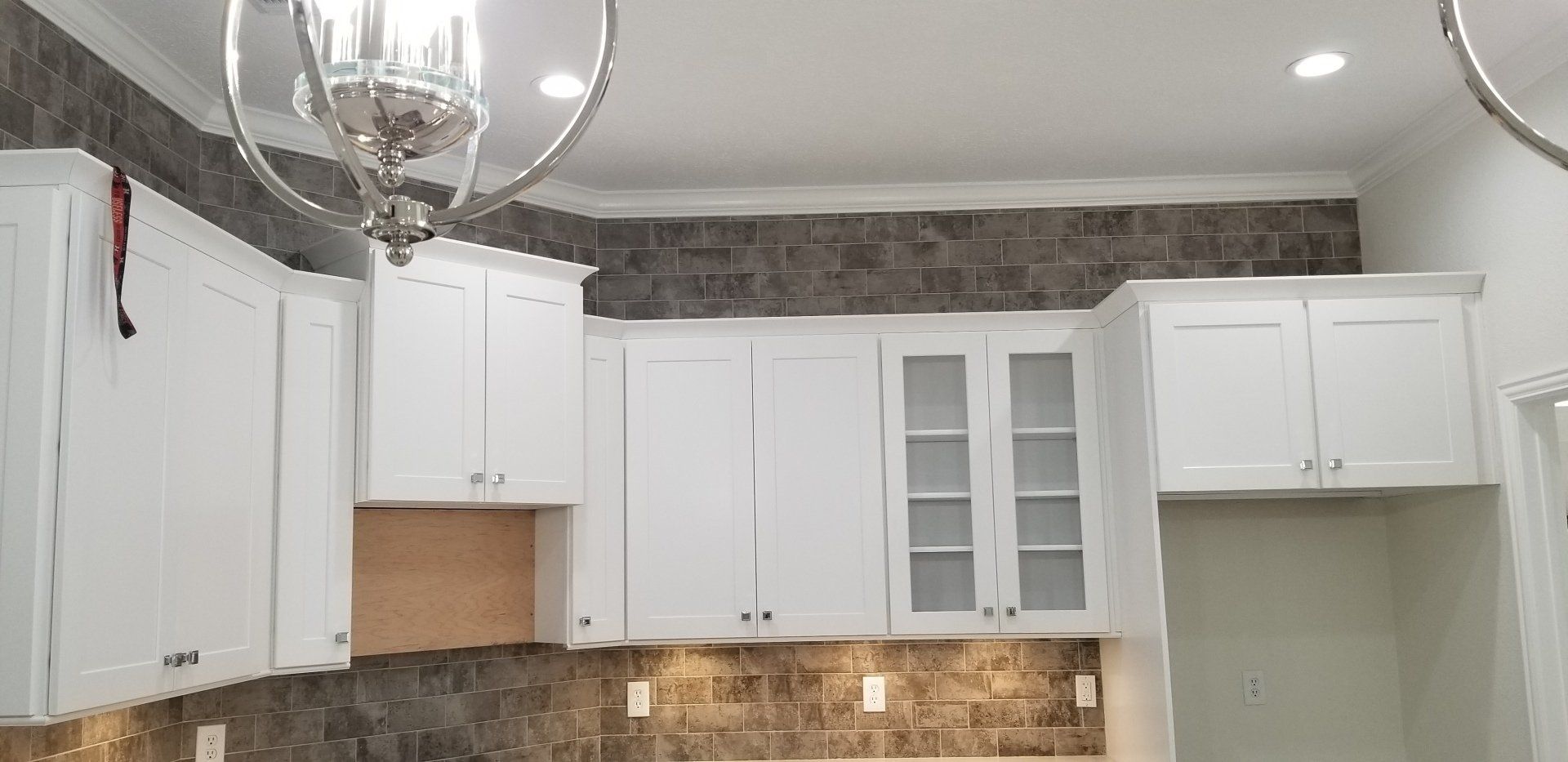 A kitchen with white cabinets and a chandelier hanging from the ceiling.
