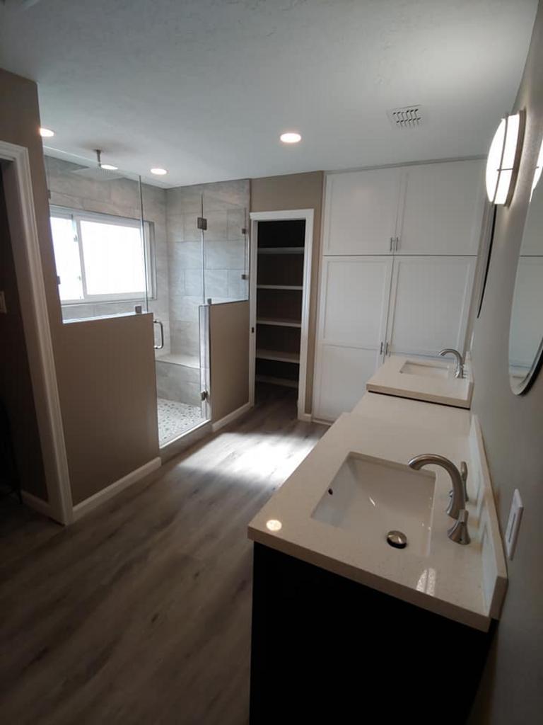A bathroom with a sink , mirror and shower.