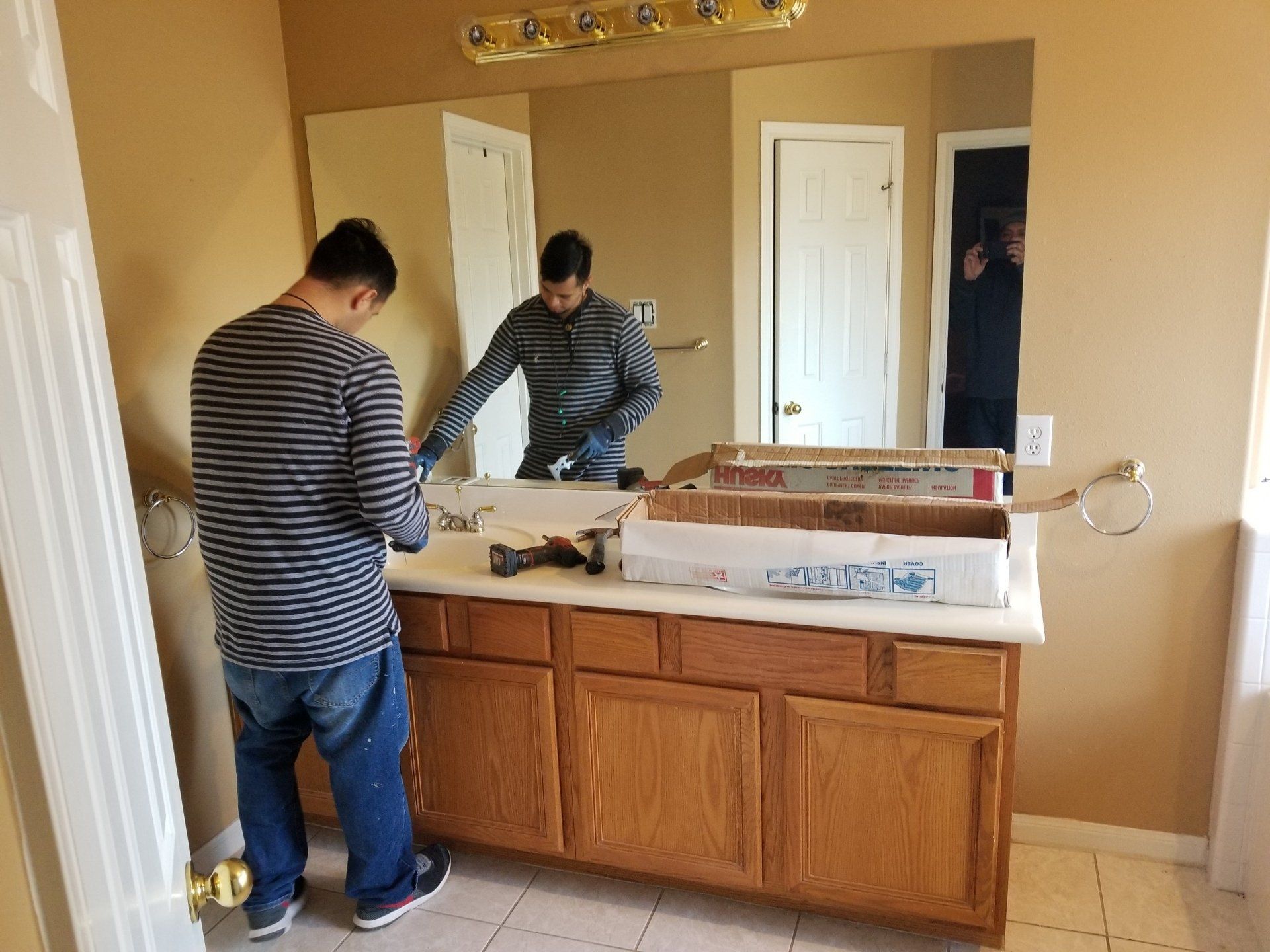 A man is standing in a bathroom looking at a mirror.