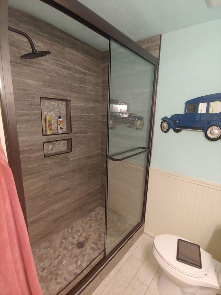 A bathroom with a shower , toilet and a car on the wall.