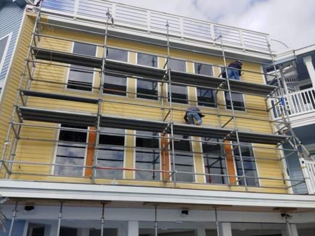 A building with scaffolding on the side of it is being painted.
