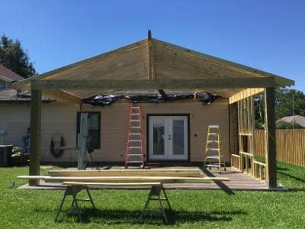 A wooden structure is being built in the backyard of a house.