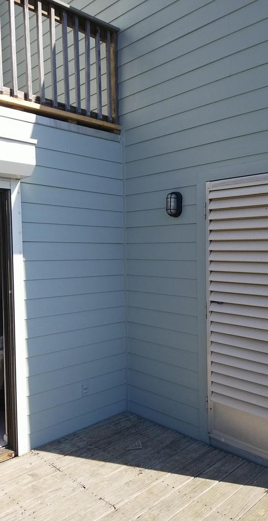 A blue house with a wooden deck and a balcony.