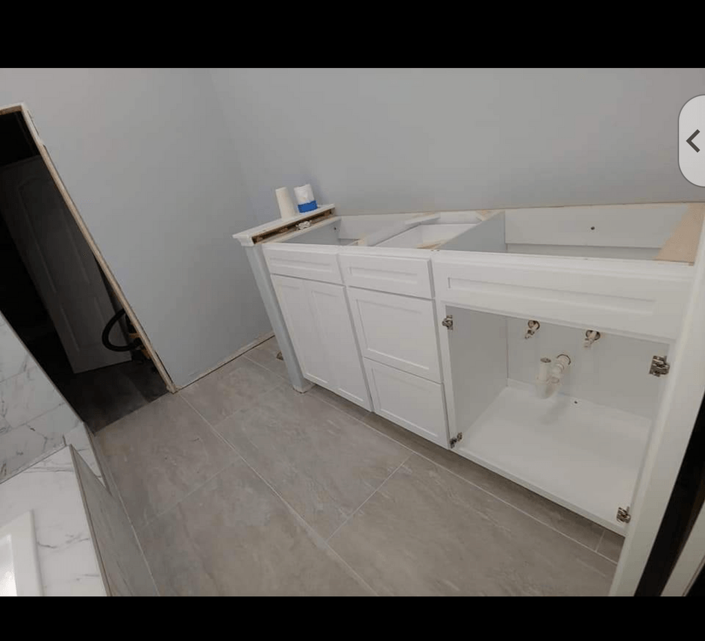 A bathroom with white cabinets and a sink underneath it.