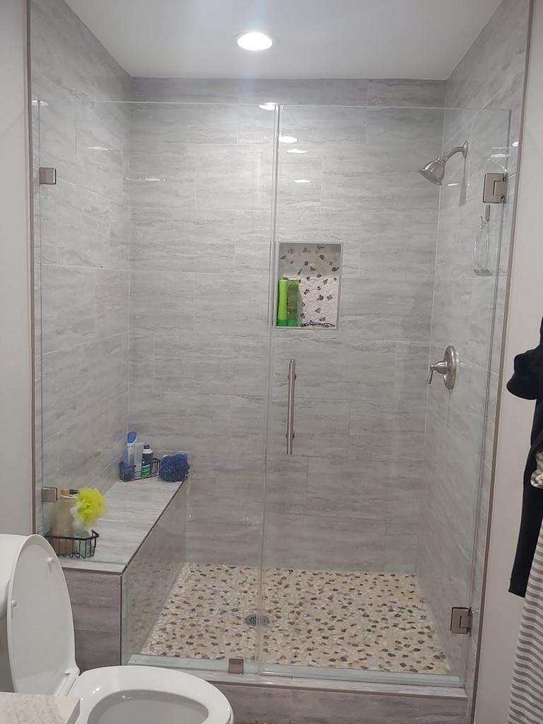 A bathroom with a toilet and a walk in shower with a glass door.