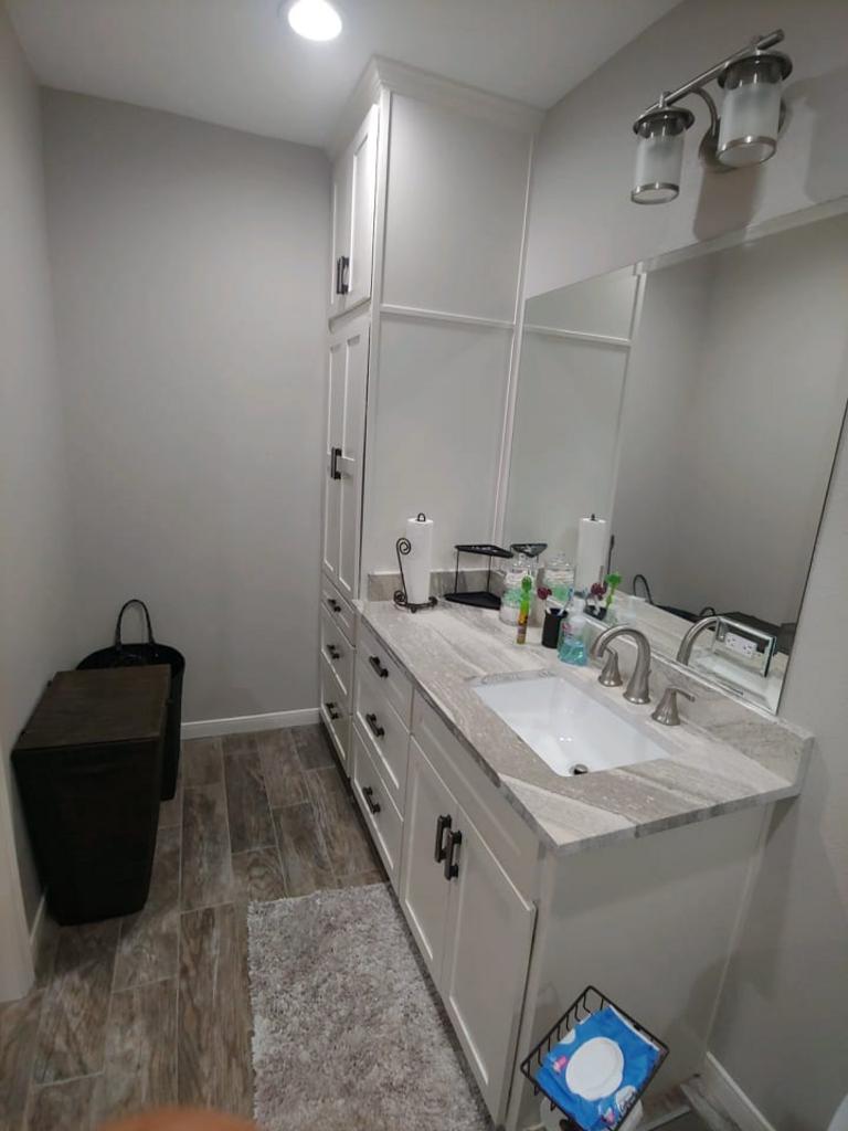 A bathroom with a sink , mirror and cabinets.