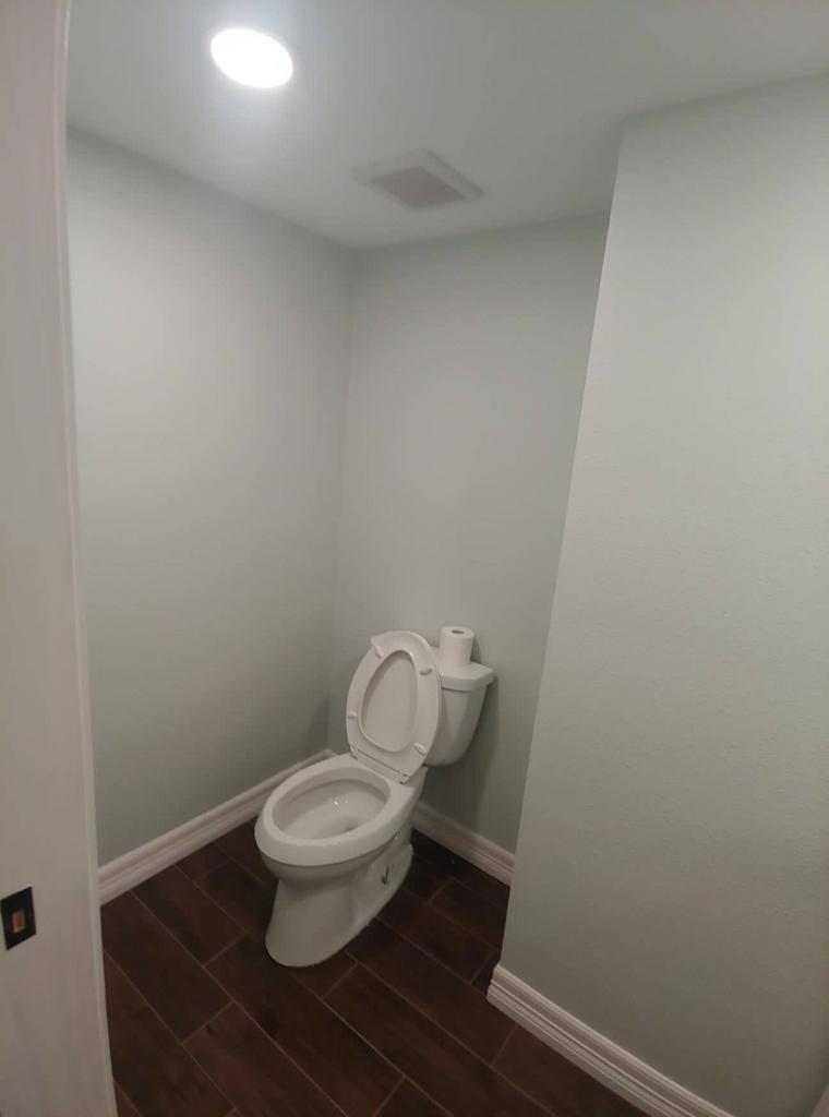 A toilet is sitting in a small bathroom next to a door.