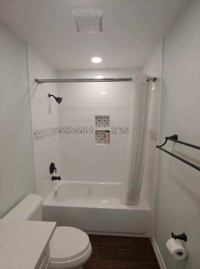 A bathroom with a toilet , bathtub and shower.