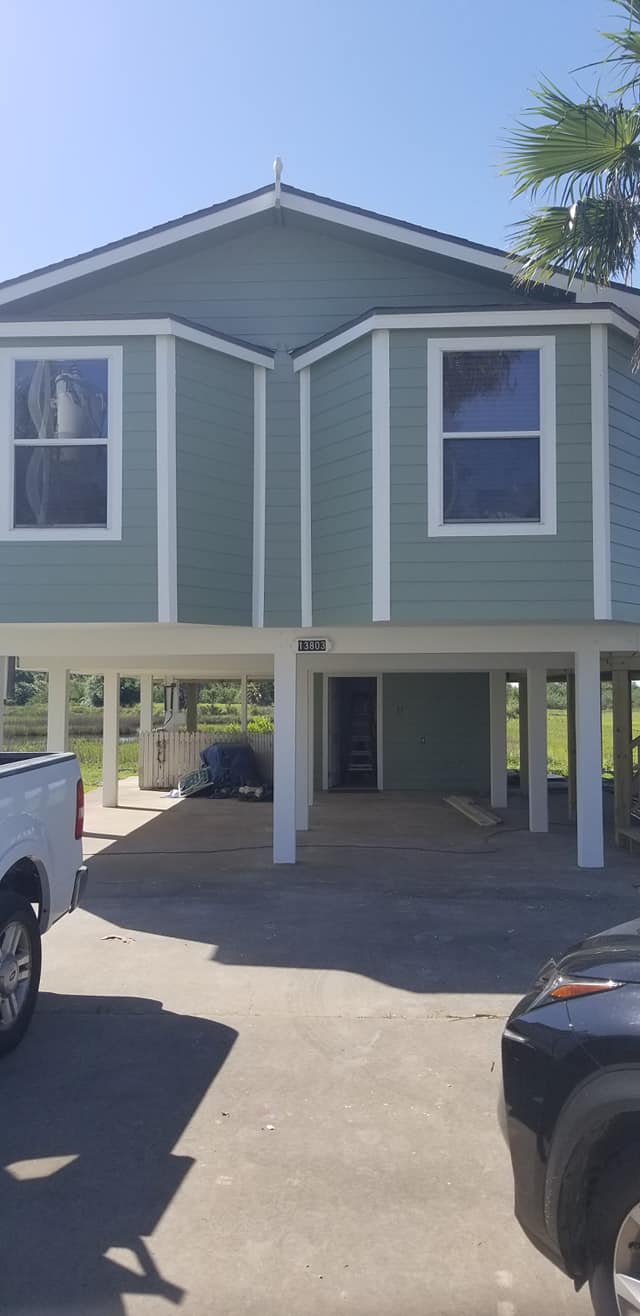 A green house with a truck parked in front of it.