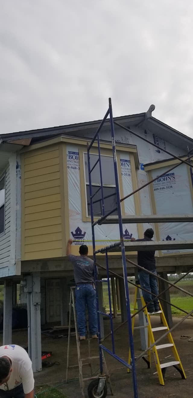 A group of men are working on the side of a house.