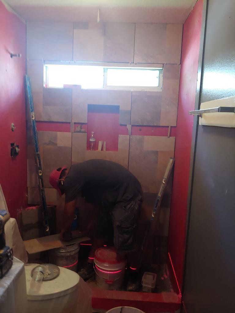 A man is working in a bathroom with red walls.