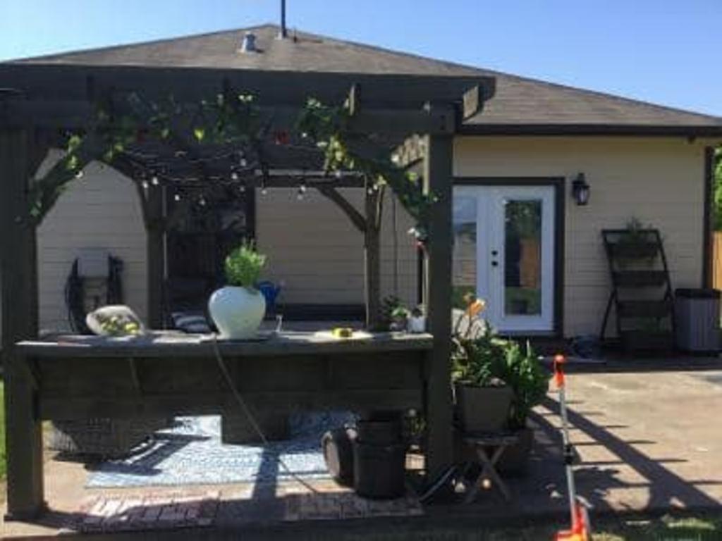 A house with a pergola and a table in front of it.