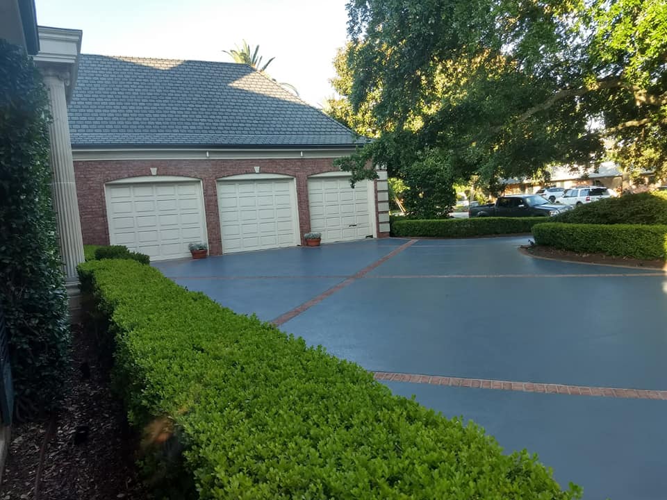 A driveway leading to a house with three garage doors
