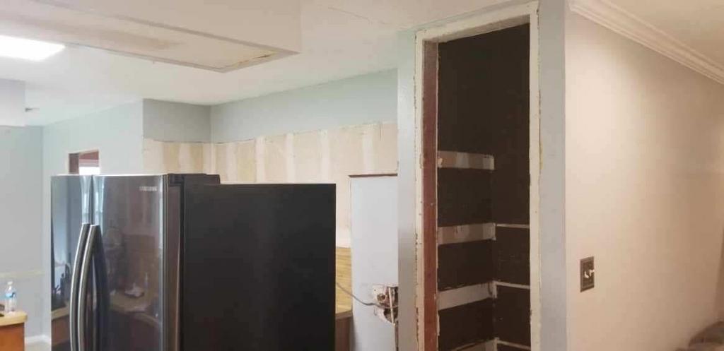 A kitchen with a refrigerator and a pantry in it.