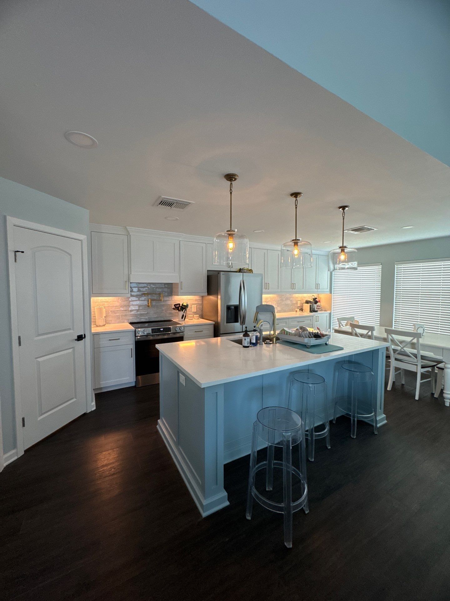 Cozy kitchen with sage green cabinets, light wood island, and black lantern lights.