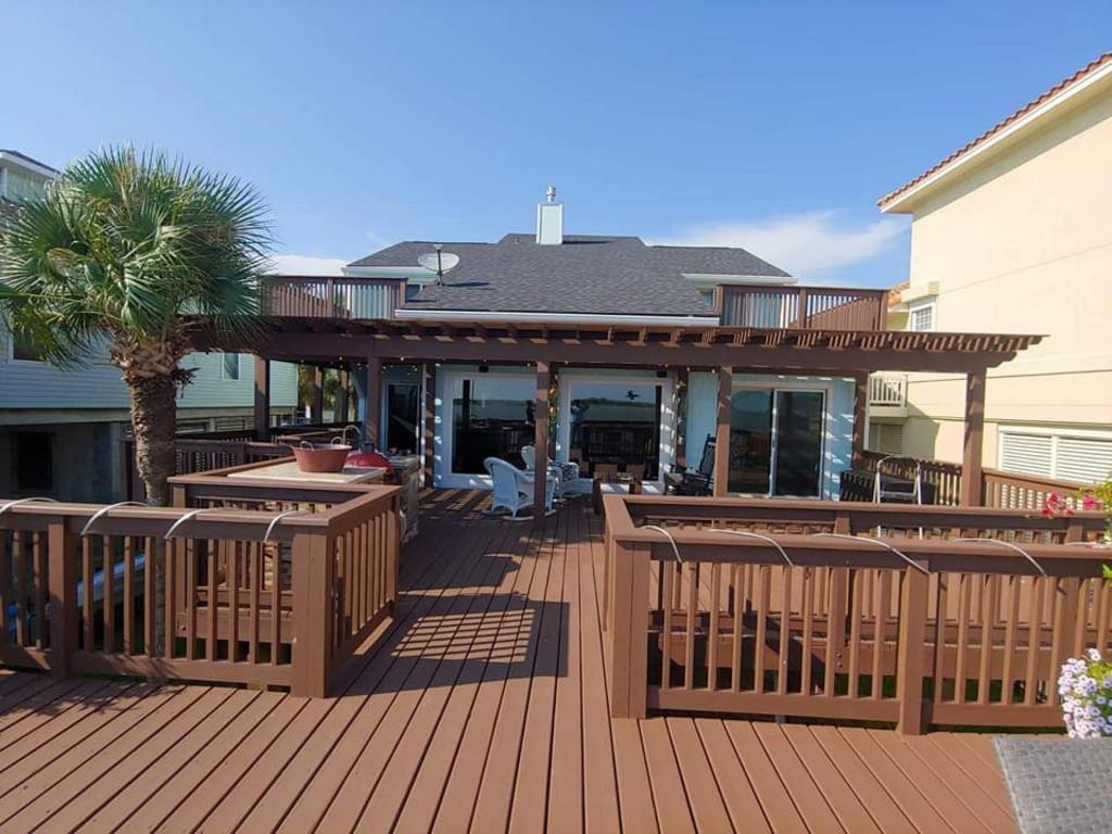 A large wooden deck with a pergola and a house in the background