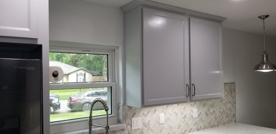 A kitchen with gray cabinets , a sink , and a window.