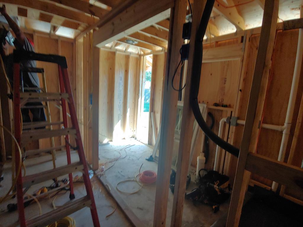 A man is standing on a ladder in a room under construction.