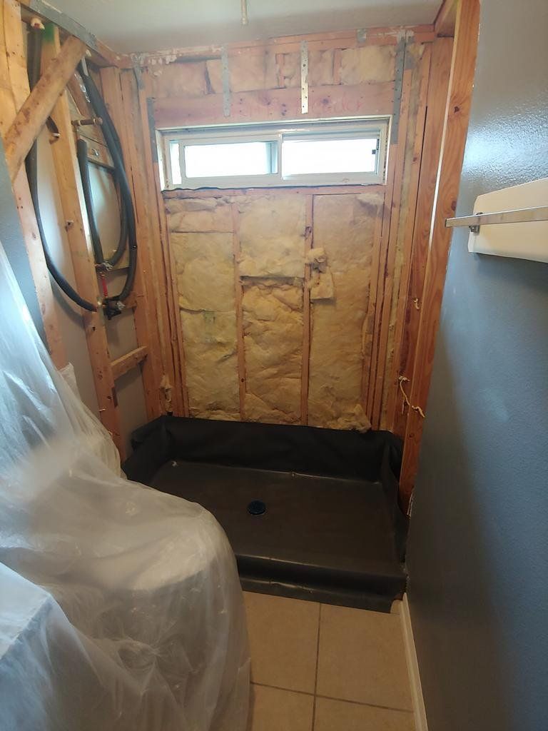 A bathroom under construction with a shower stall and a window.