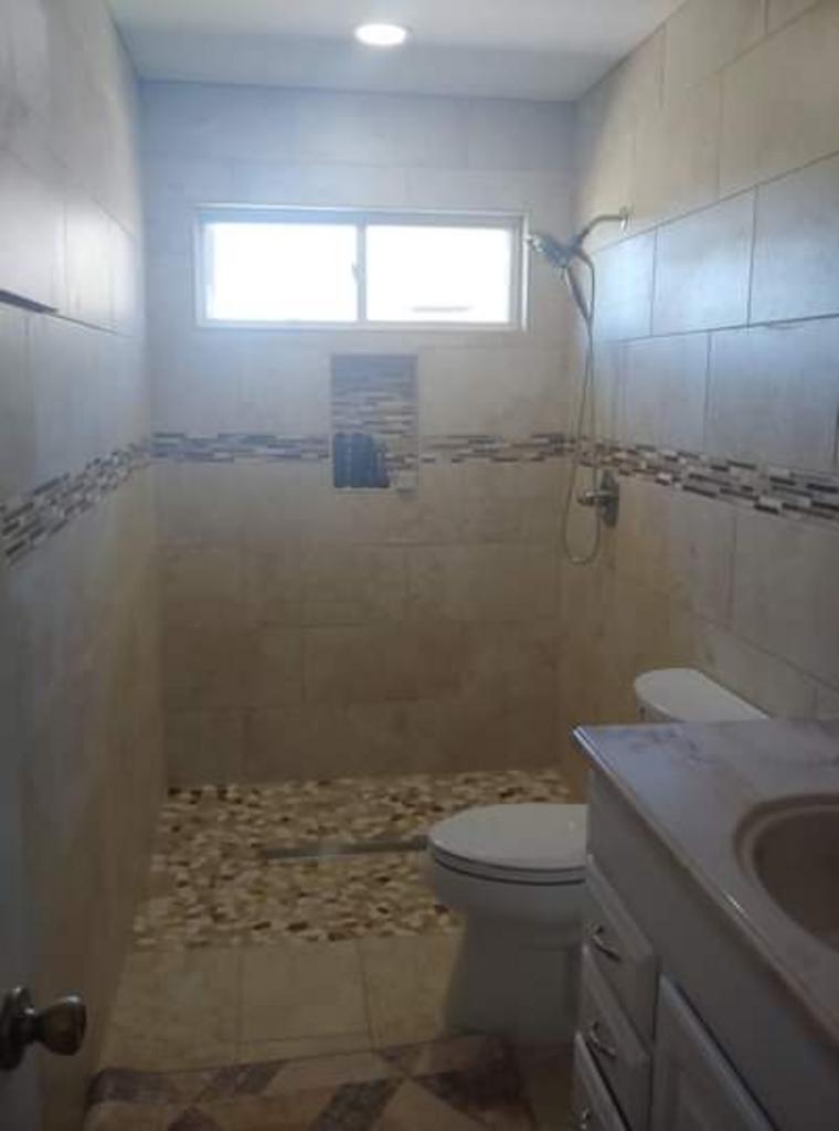 A bathroom with a toilet , sink and shower.
