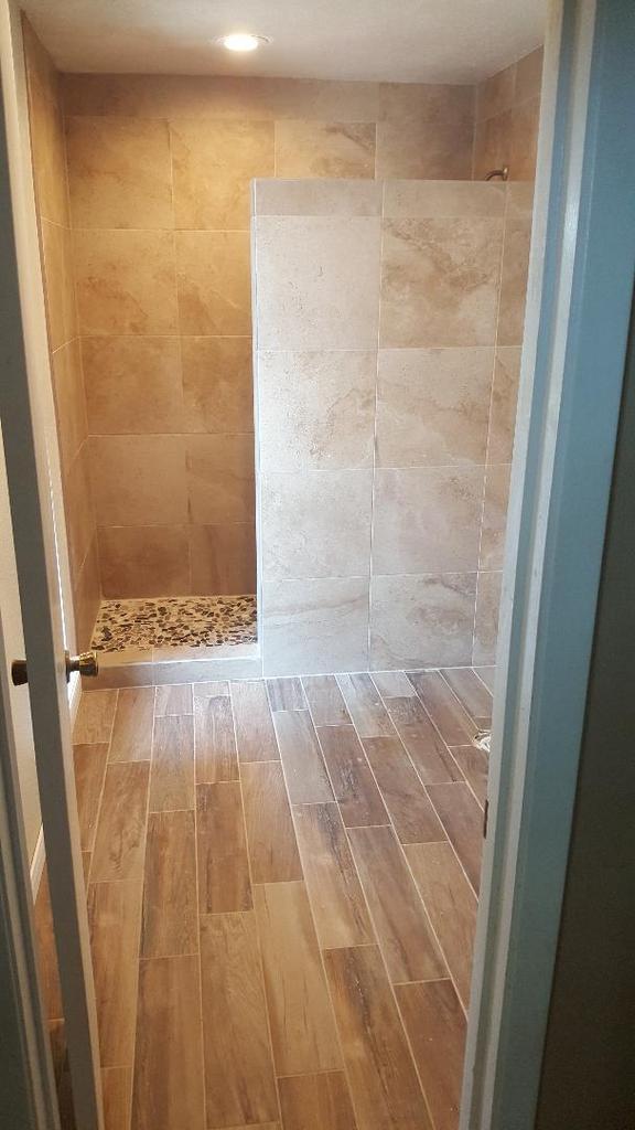 A bathroom with a walk in shower and wooden floors.