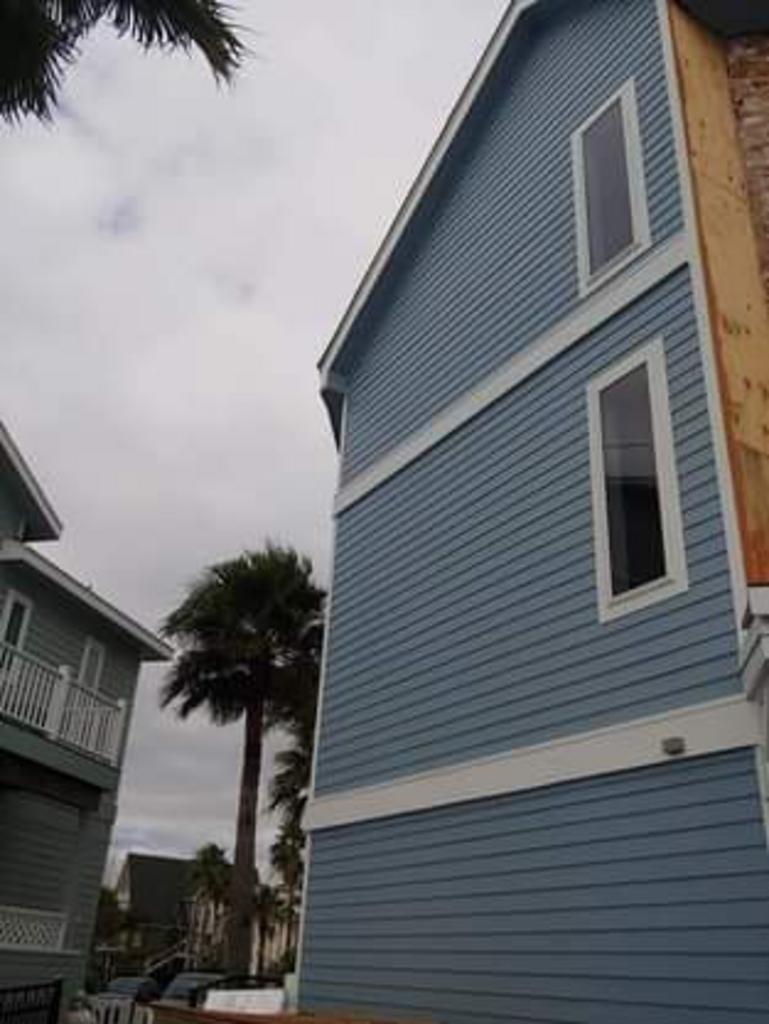 A blue and white house with a palm tree in the background.