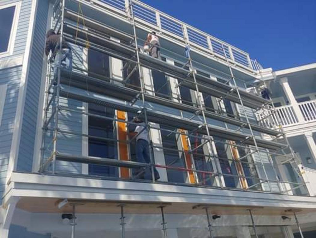 A group of people are painting a building with scaffolding.