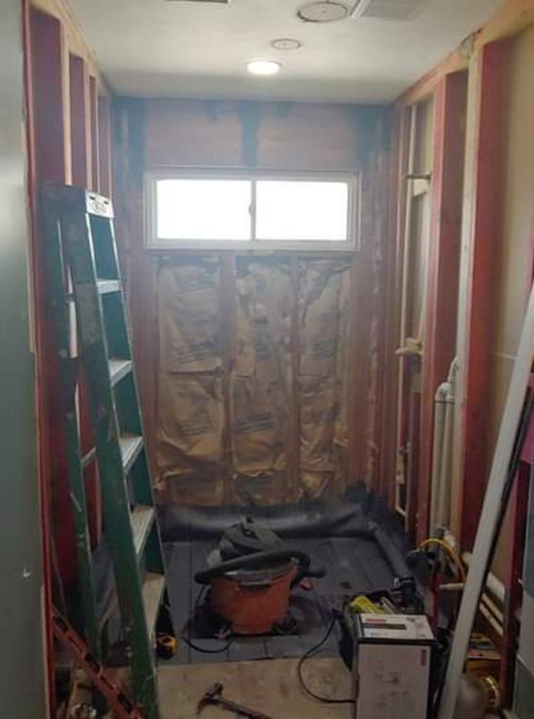 A bathroom under construction with a window and a ladder.