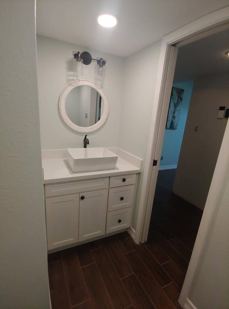 A bathroom with a sink , mirror and cabinets.