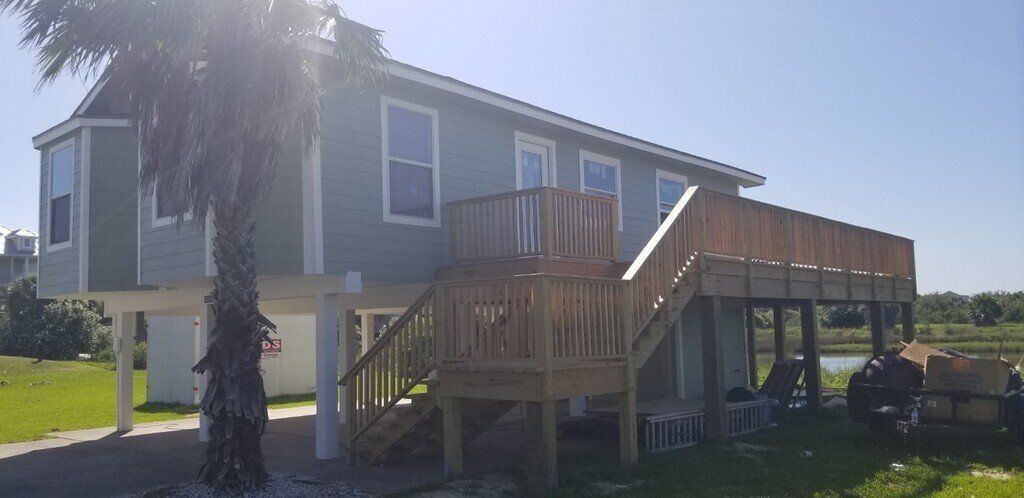 A house on stilts with a large deck and stairs.