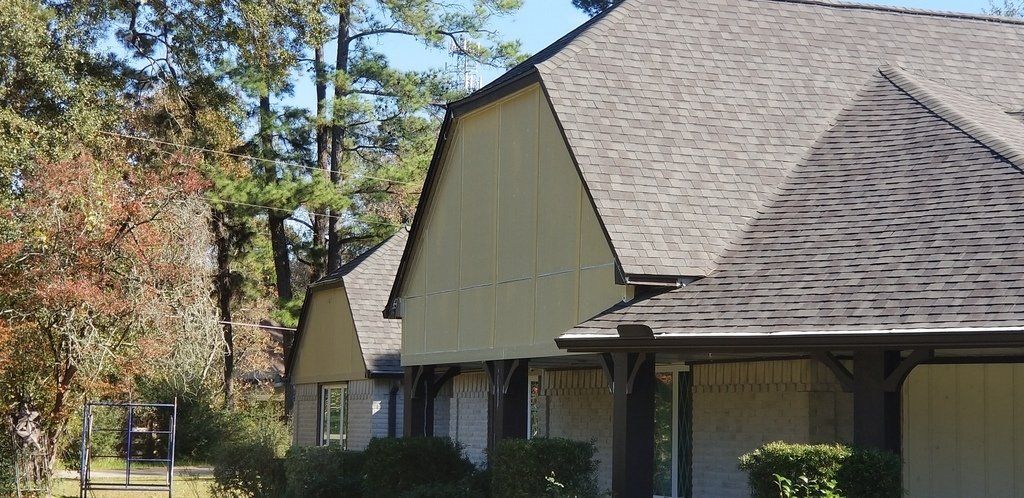 A row of houses with a gray roof and trees in the background
