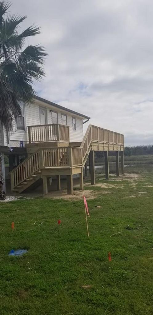 A house with a wooden deck and stairs in front of it.
