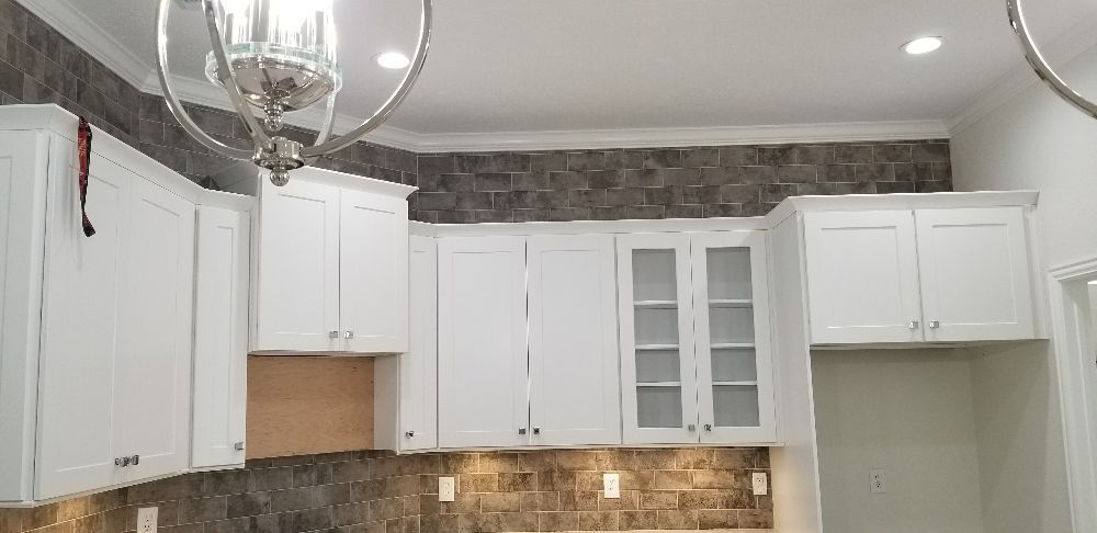 A kitchen with white cabinets and a chandelier hanging from the ceiling.
