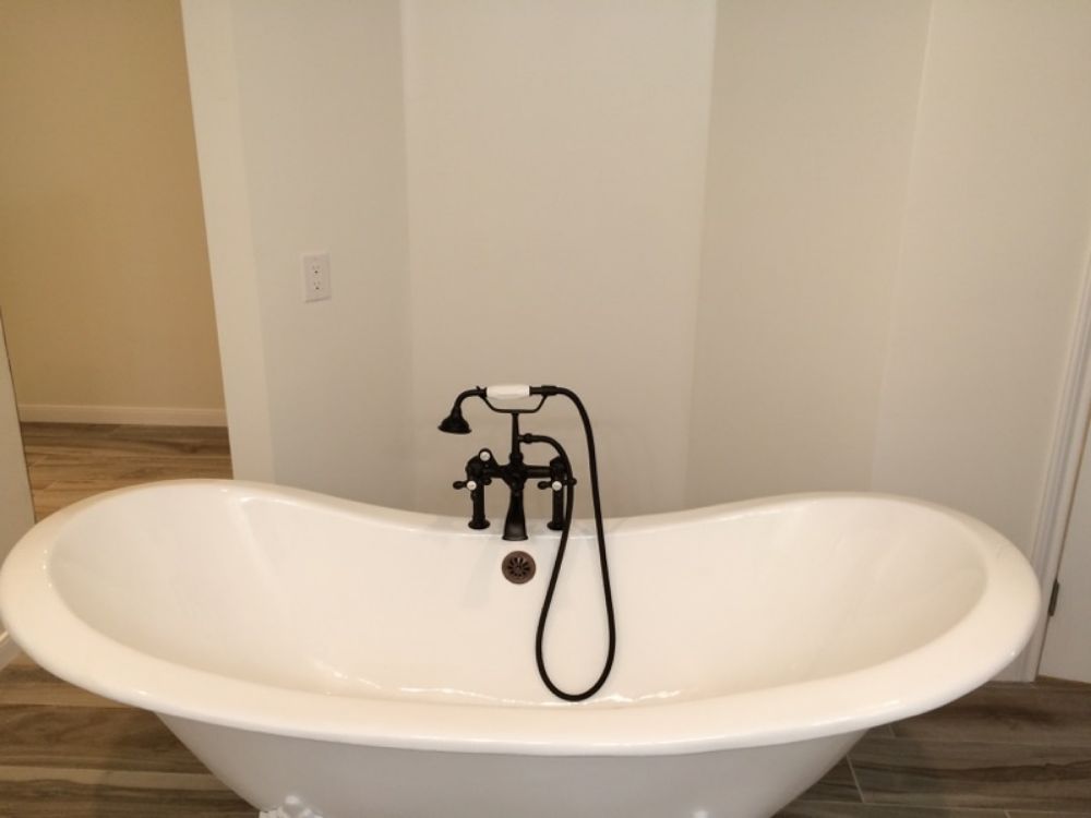 A white bathtub with a black faucet attached to it in a bathroom.