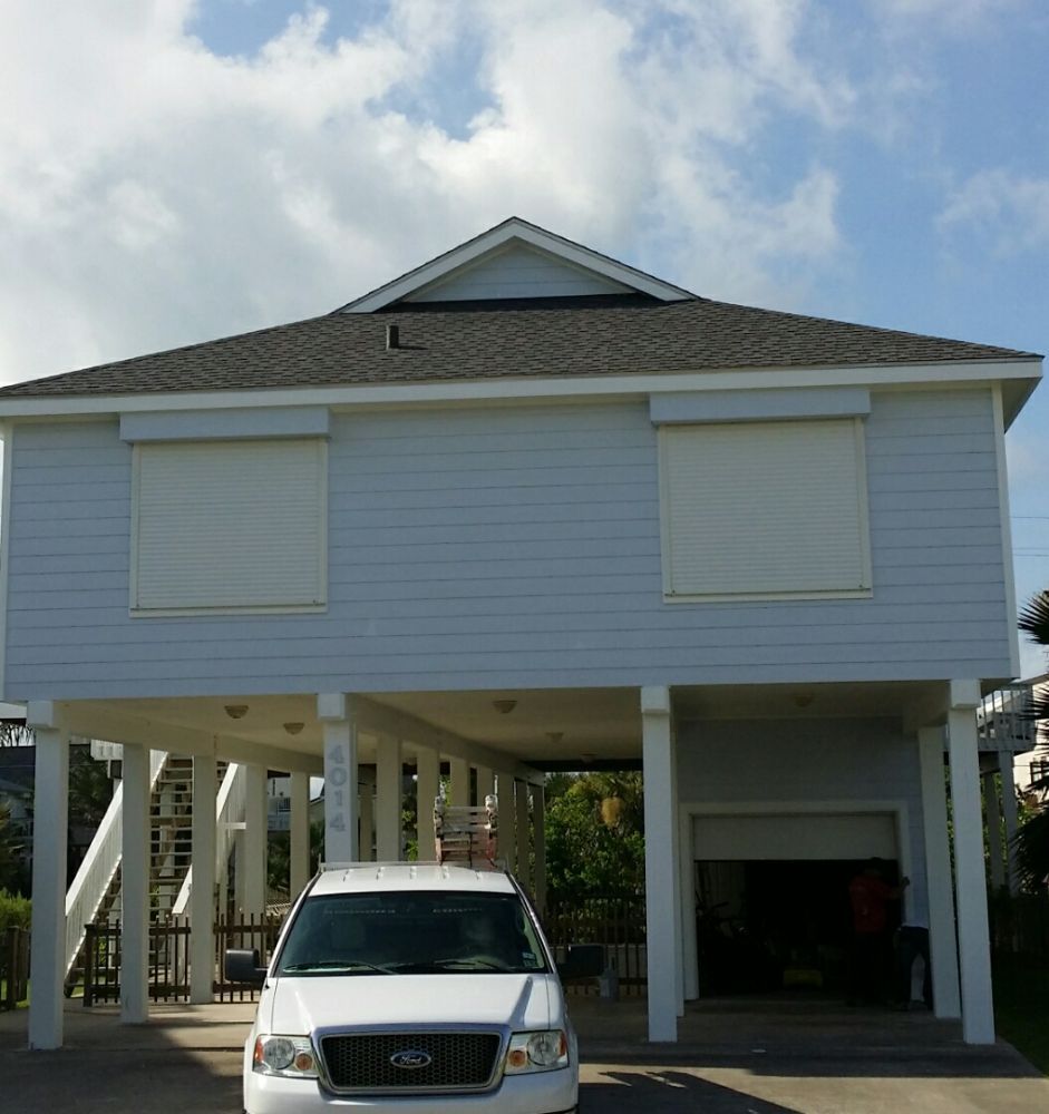 A white car is parked in front of a white house
