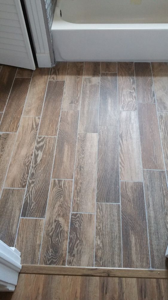 A bathroom with a wooden floor and a bathtub.