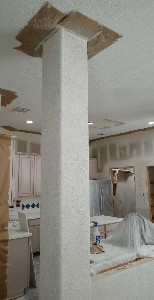 A kitchen with a pillar in the middle of the room.