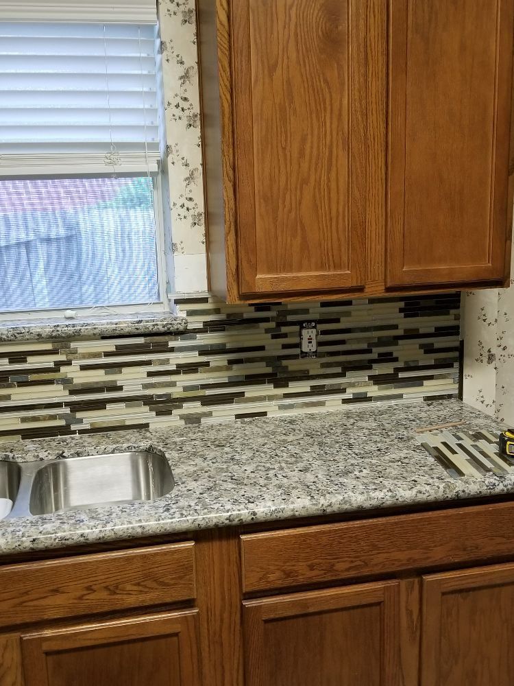 A kitchen with granite counter tops , wooden cabinets , a sink and a window.